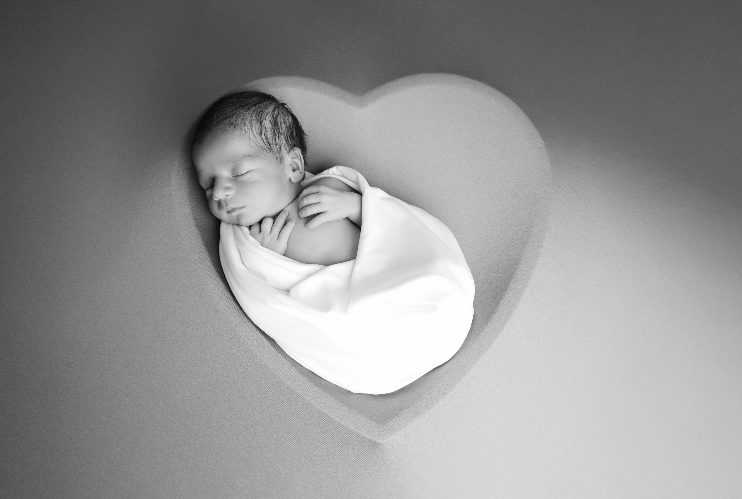Nouveau-né emmailloté en forme de cœur lors d'une séance naissance